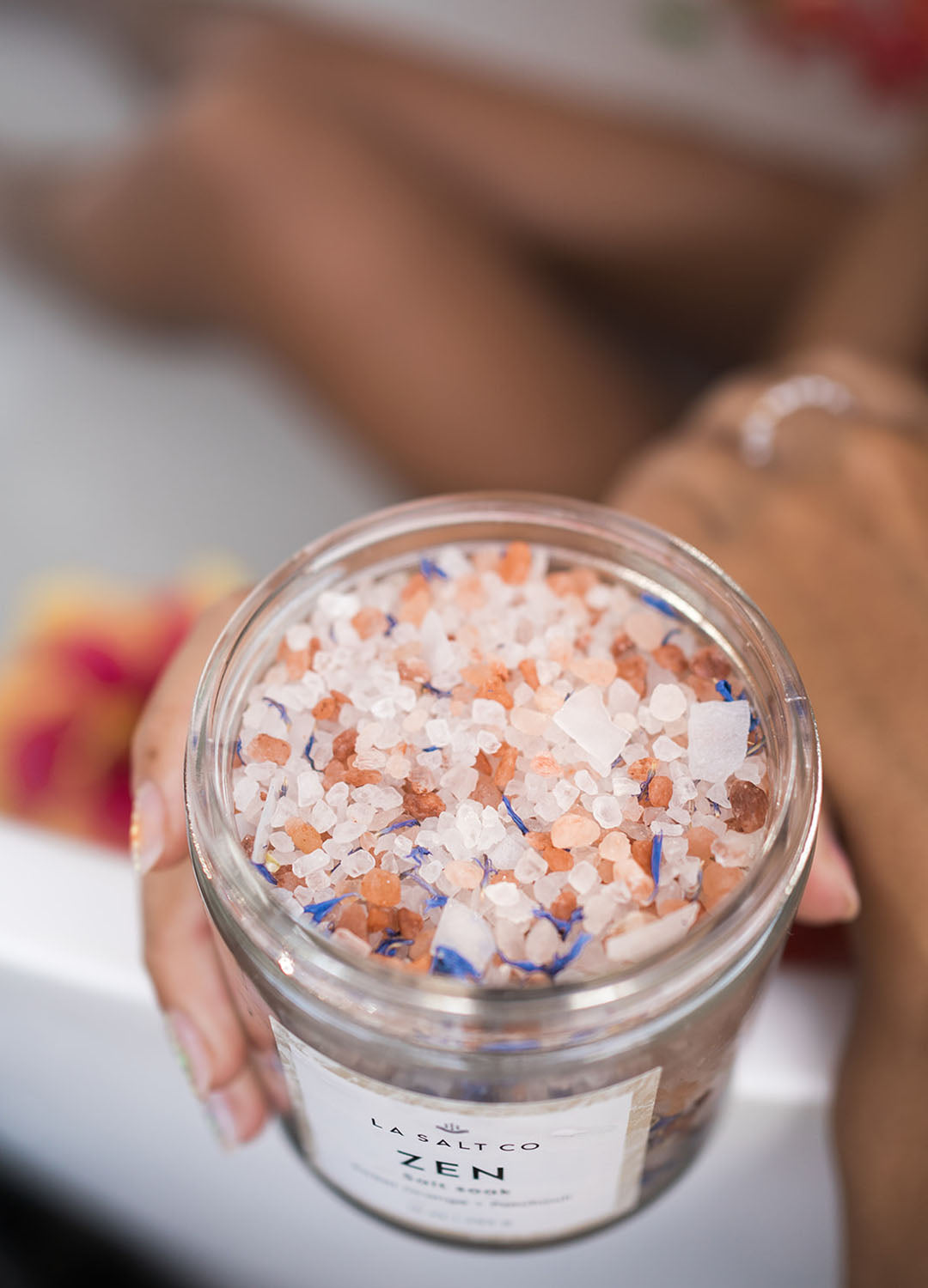 A woman holding a Zen Salt Soak in a bath